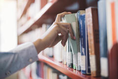 A person pulling a book from a shelf