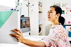 Womale putting away files while sitting at her desk in her home office. 
