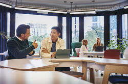 2 males having a discussion at a table with tablet in front of them