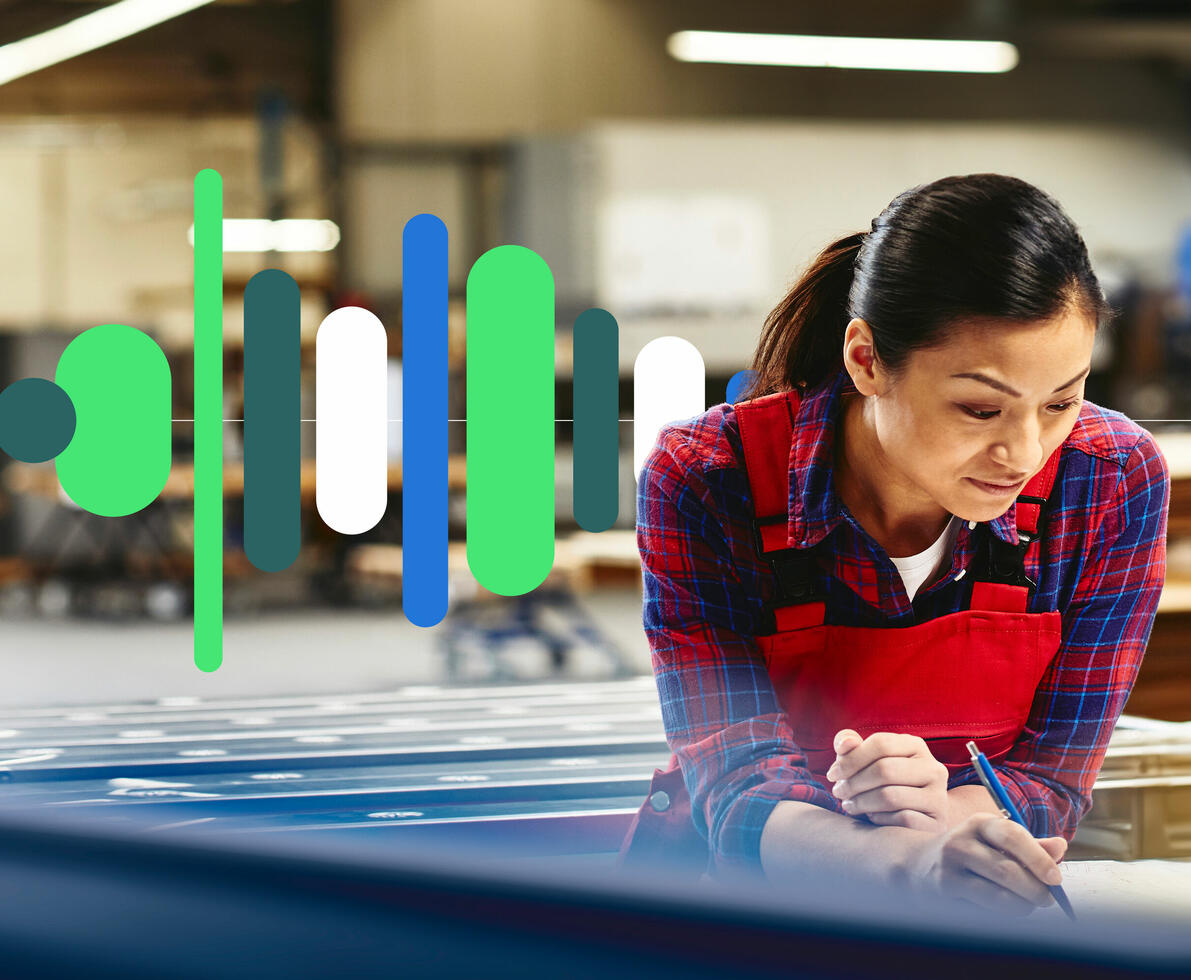 Woman wearing a red overall writing on a paper in a production site/factory.