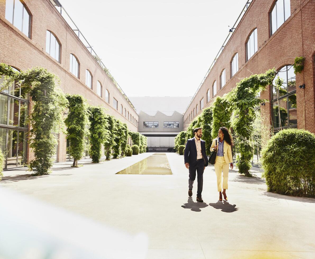 Man and woman walking outside between office buildings. Man and woman walking outside between office buildings.