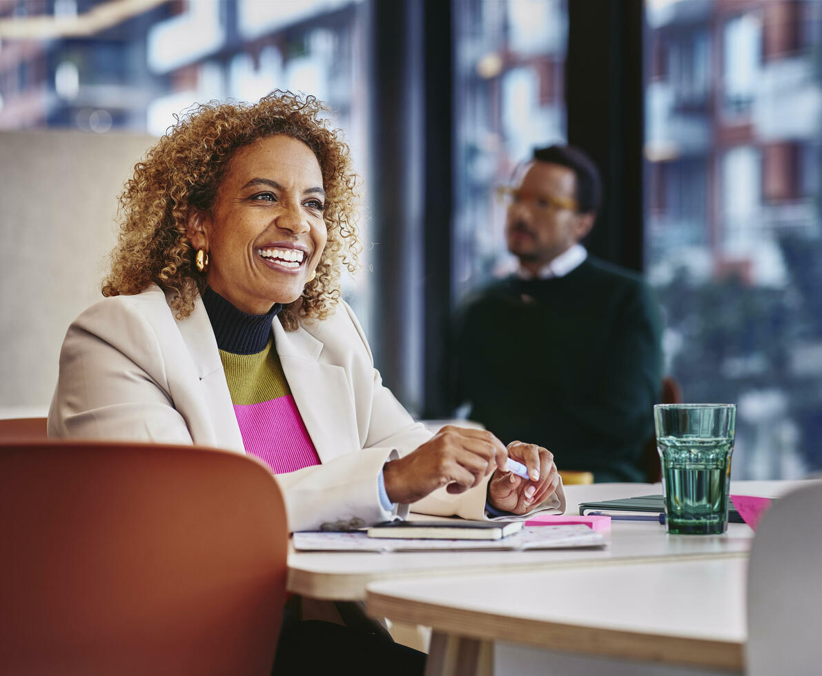 Female smiling, sitting on a table with pen in her hands Female smiling, sitting on a table with pen in her hands