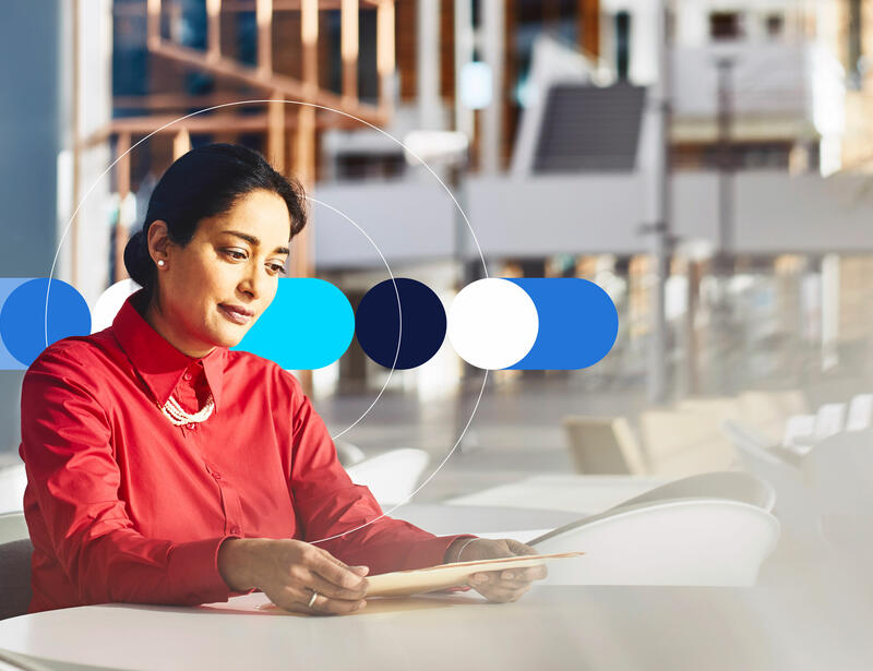 Woman sitting at a table in an office looking at a file.